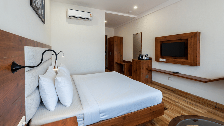 Side view of a Club Balcony Room featuring a bed with a fancy bedside light and a sleek wooden wardrobe in the background at DLS The Classio